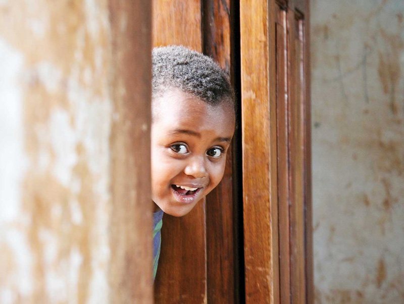 a little boy smiling and peeking out of a doorway